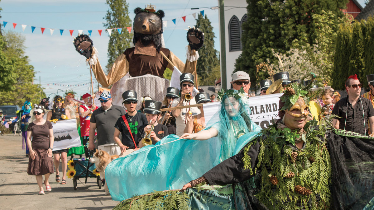 Community members in forest-themed costumes marching in the Cumberland Victoria Day Parade
