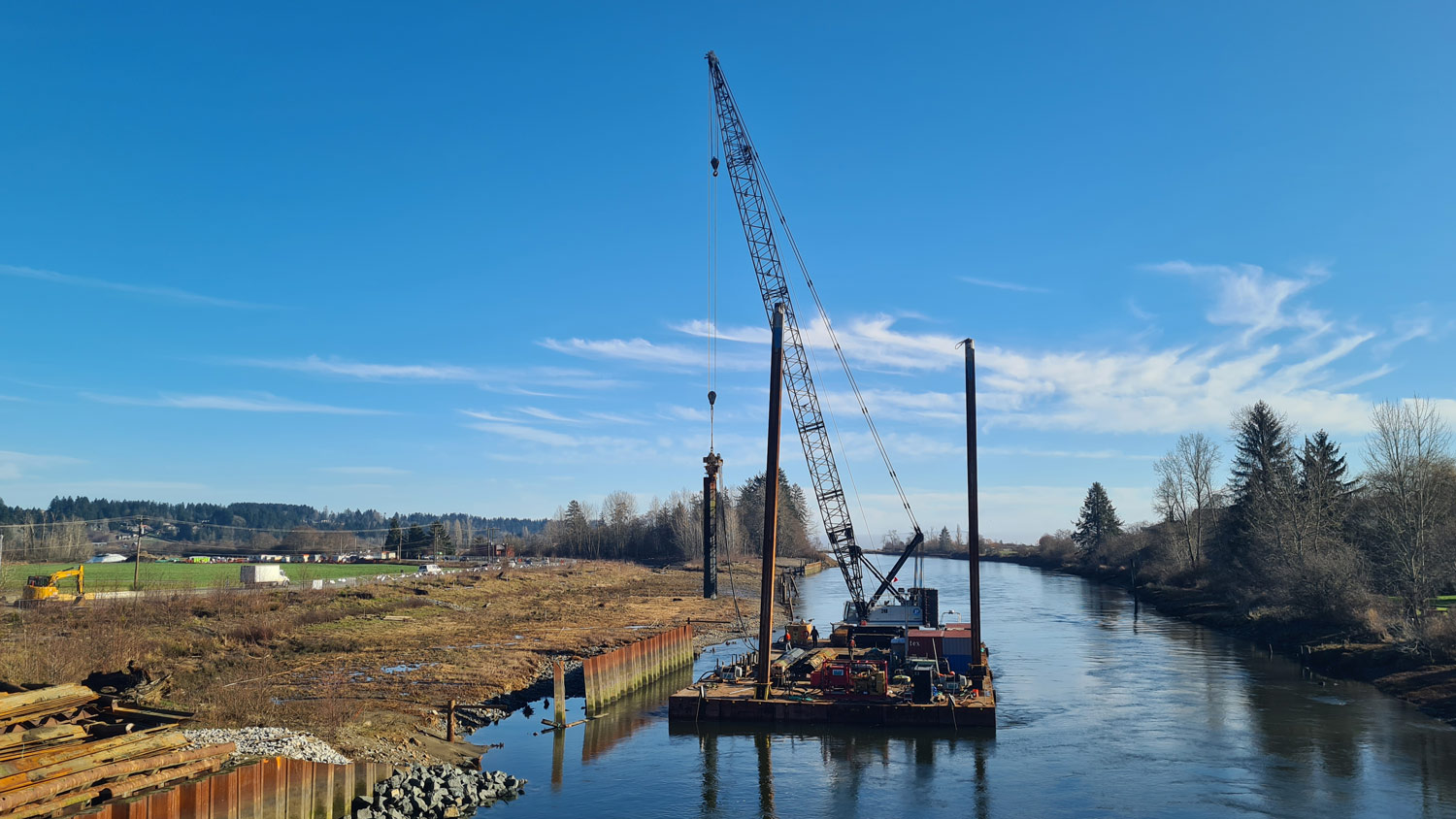 Construction crane on a barge removing a wall from a river